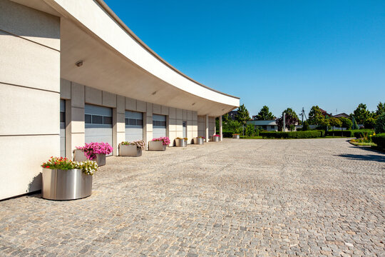 Building of multicar garage with wide access road on grounds of respectable mansion in summer
