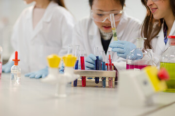 Fototapeta premium Girl students conducting scientific experiment in laboratory classroom