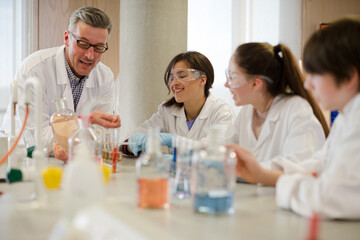 Male teacher and students conducting scientific experiment in laboratory classroom