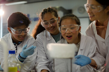 Obraz premium Female teacher and students watching scientific experiment chemical reaction in laboratory classroom
