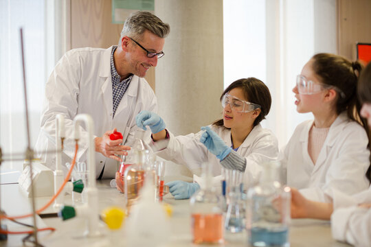 Male teacher and students conducting scientific experiment in laboratory classroom