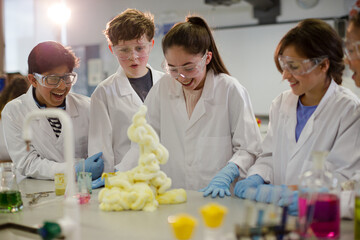 Surprised students conducting exploding foam scientific experiment in classroom laboratory