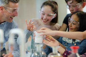 Male teacher and students watching chemical reaction, conducting scientific experiment in...