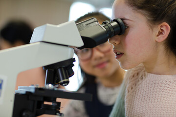 Close up profile girl student using microscope, conducting scientific experiment - Powered by Adobe