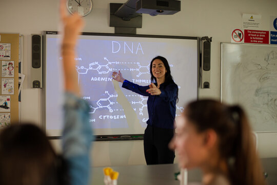 Female science teacher teaching DNA lesson at projection screen