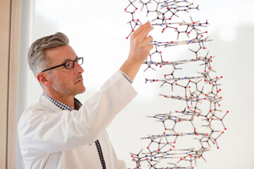 Serious male teacher examining hanging molecular structure