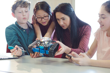Fototapeta premium Female teacher and students playing with robot in classroom