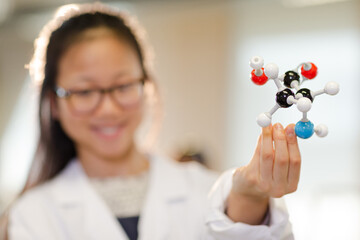 Portrait smiling, confident girl student holding molecular structure in laboratory classroom