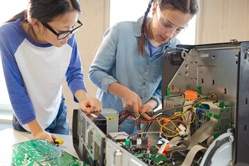 Girl students assembling computer in classroom