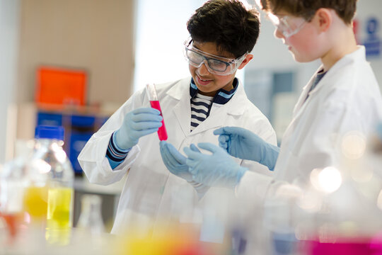 Boy students examining liquid in test tube, conducting scientific experiment in laboratory classroom