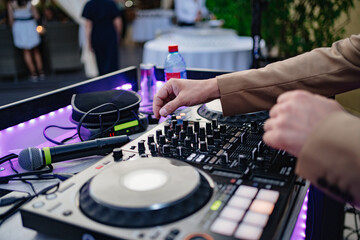 Fototapeta na wymiar DJ's hands on music equipment. Mixers, turntables, switching, acoustics. 