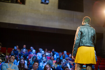 Female speaker on stage talking to audience