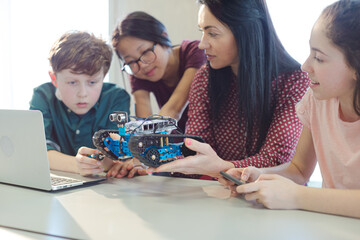 Fototapeta premium Female teacher and students playing with robot in classroom