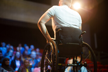 Audience watching speaker in wheelchair talking on stage