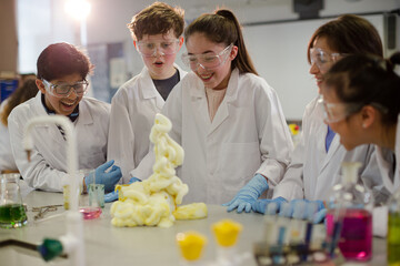 Surprised students conducting exploding foam scientific experiment in classroom laboratory