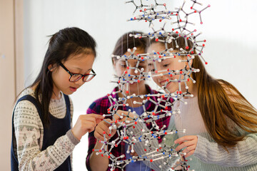 Curious girl students examining molecular structure in classroom
