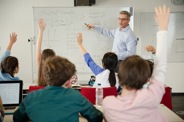Naklejka na ściany i meble Male teacher leading lesson at whiteboard in classroom