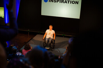 Fototapeta na wymiar Attentive audience listening to female speaker in wheelchair on stage