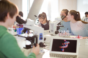 Student conducting scientific experiment at microscope in laboratory classroom