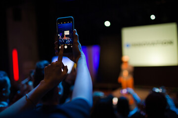Eager audience with smart phone flashlights in dark auditorium