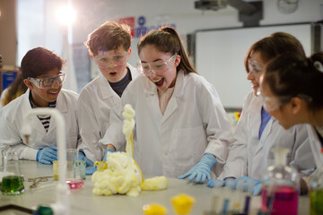 Surprised students conducting exploding foam scientific experiment in classroom laboratory