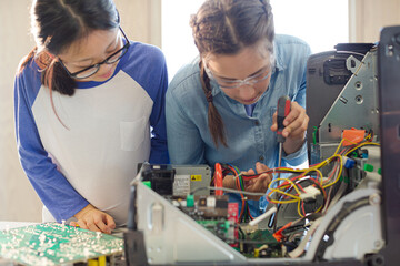 Girl students assembling computer in classroom