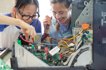 Girl students assembling computer in classroom