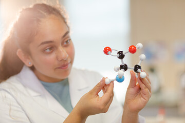 Curious girl student examining molecular structure in laboratory classroom - Powered by Adobe