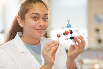 Curious girl student examining molecular structure in laboratory classroom