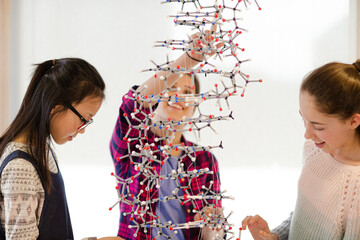 Curious girl students examining molecular structure in classroom