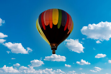 Fototapeta premium Colorful hot air balloon flying against blue clouds sky. Beautiful Inspiration or travel background, fly above the clouds, colorful hot air balloon in blue sky