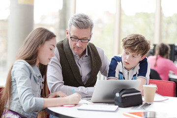 Fototapeta premium Male teacher and students using laptop at table
