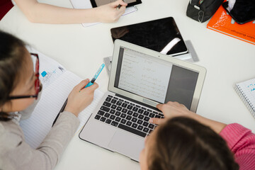 Girl students using laptop at table