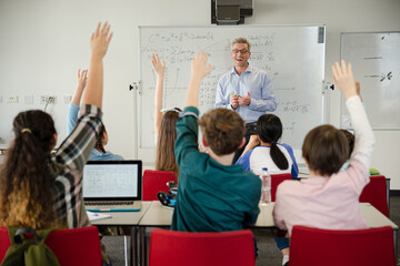 Male teacher leading lesson at whiteboard in classroom