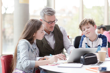 Fototapeta premium Male teacher and students using laptop at table