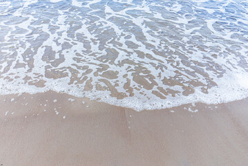Wave of the sea on sandy beach white foam.Top view of a wave breaking on the sand at the beach. Top view,Copy space.
