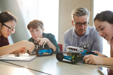 Male teacher and students playing with robot in classroom