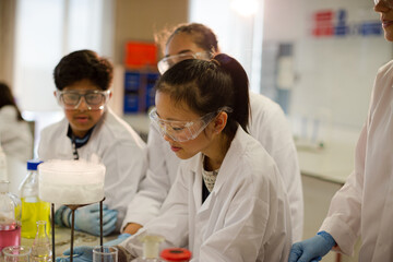 Female teacher and students watching scientific experiment chemical reaction in laboratory classroom