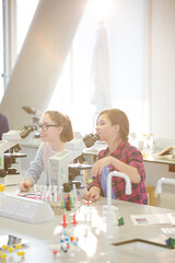 Eager girl students behind microscopes in laboratory classroom