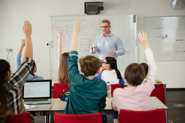 Naklejka na ściany i meble Male teacher leading lesson at whiteboard in classroom