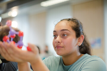 Curious girl examining molecule model in classroom