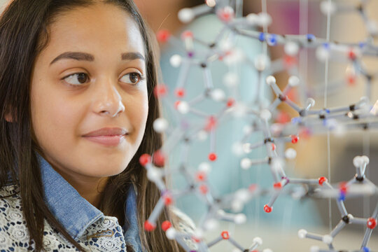 Portrait smiling girl student holding molecular model in laboratory classroom