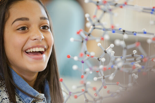 Portrait smiling girl student holding molecular model in laboratory classroom