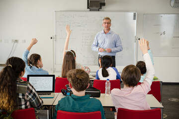 Male teacher leading lesson at whiteboard in classroom