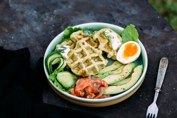 Belgian waffles with salmon, avocado and egg in a plate
