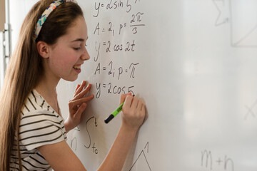 Girl student writing at whiteboard in classroom