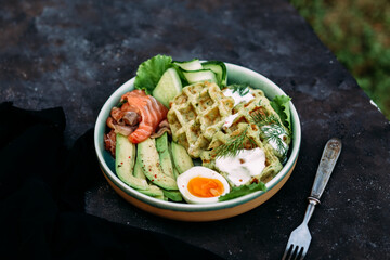 Belgian waffles with salmon, avocado and egg in a plate