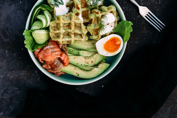 Belgian waffles with salmon, avocado and egg in a plate