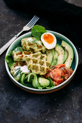 Belgian waffles with salmon, avocado and egg in a plate