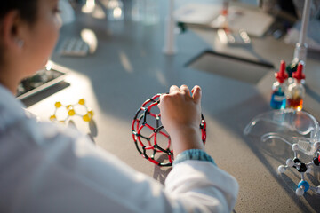 Girl student examining and touching molecular structure in classroom